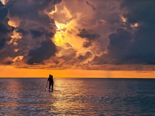 A person on stand up paddleboard during sunrise