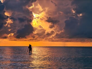 A person on stand up paddleboard during sunrise