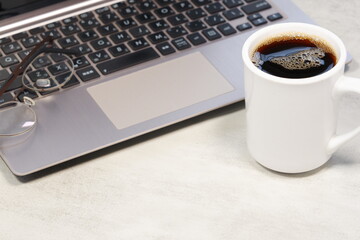 淹れたての美味しいコーヒーを飲みながら、ノートパソコンでデスクワークをしているイメージ	
