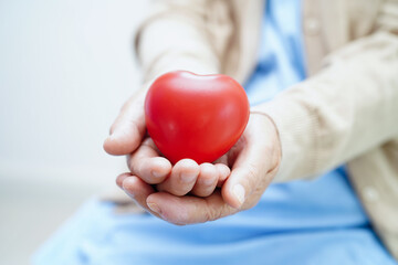 Asian elder senior woman patient holding red heart in hospital.