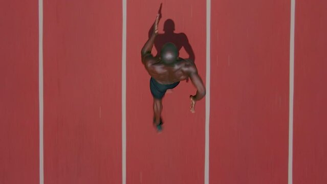 Top view of an African ethnicity athlete man running on the stadium followed by a drone