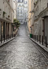 Perspective view of one of the old montmartre streets in Paris. A narrow cobblestone street with typical French architecture descends and rises, The historic district of Montmartre in the city of Pari