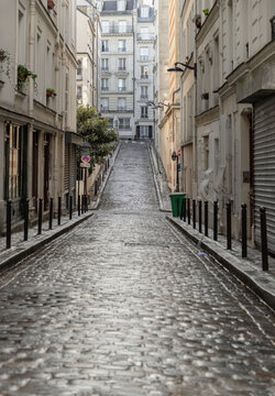 Perspective view of one of the old montmartre streets in Paris. A narrow cobblestone street with typical French architecture descends and rises, The historic district of Montmartre in the city of Pari