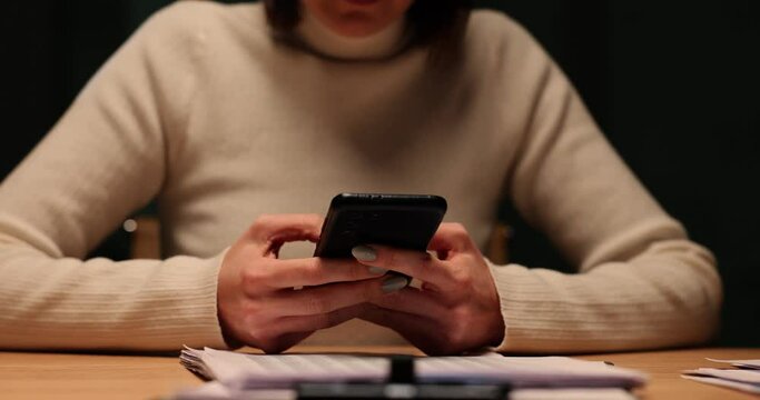 Woman uses her phone at desk late at night