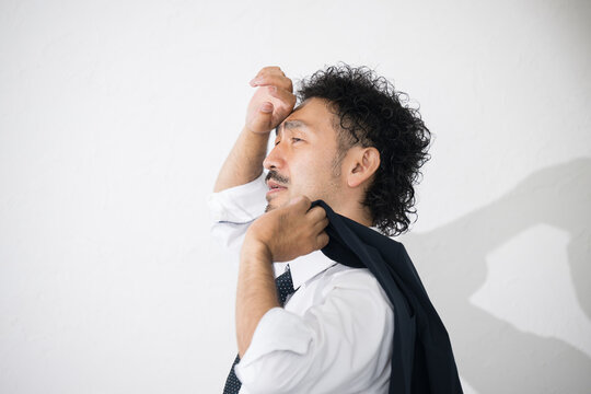 A man shading himself from the blinding sunlight on a hot, sweltering day in the summer sun, his suit sweating nonstop.