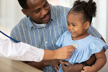 closeup doctor hands holding stethoscope and listening to African child patient's breath beside her...