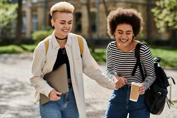 Young multicultural lesbian couple, stylish and casual, holding hands while walking down a...