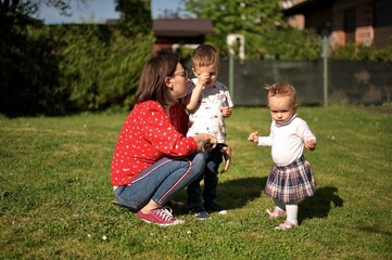 Mother with two little children playing in the back yard