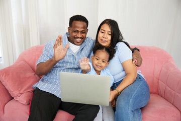 African American father and asian mother with daughter using laptop computer and online video call...