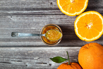 Delicious homemade orange jam. Close-up of a teaspoon over a glass jar