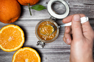 Man holding a teaspoon with orange jam. Delicious homemade orange jam, healthy breakfast.