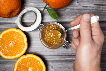 Man holding a teaspoon with orange jam. Delicious homemade orange jam, healthy breakfast.