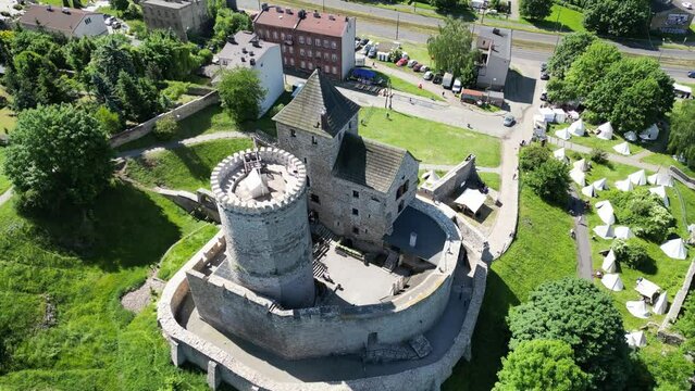 Medieval Bedzin castle with a turret, walls, and courtyard during a beautiful summer day surrounded by lush greenery, grass, and trees