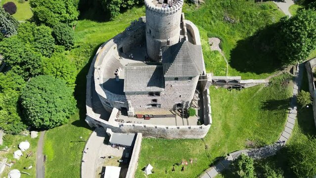 Medieval Bedzin castle with a turret, walls, and courtyard during a beautiful summer day surrounded by lush greenery, grass, and trees.