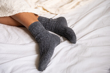 Females feet wearing woolen socks. Woman resting in bed