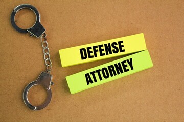 iron handcuffs and colored paper with the word defense attorney. the concept of guilt in court