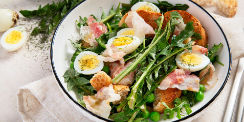 Summer fresh salad from dandelion leaves, eggs, bacon and with bread on light background