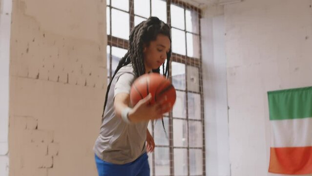 Slowmo of two Biracial male and female basketball players practicing ball dribbling on indoor court