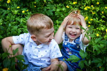 Cute kids in flowers in nature. Funny Boy and girl in the grass. A good environment means Healthy,...