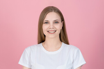 Portrait of attractive happy caucasian young blonde woman in casual white t-shirt isolated on pink...