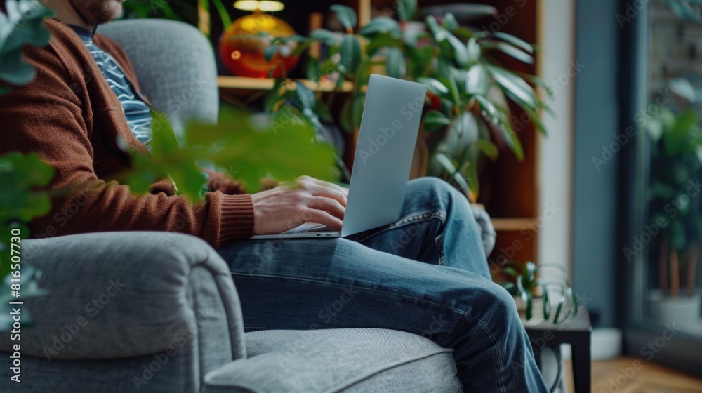 Poster A man sitting on a couch while using a laptop. Suitable for technology and remote work concepts
