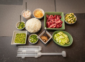 Sushi Ingredients arranged on a grey granite surface with ingredients such as ahi tuna, rice, green...