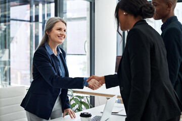 Mature businesswoman, handshake and meeting in office with employee, greeting and onboarding in company. Female ceo, recruitment and hand gesture at desk for agreement, support and contract in hiring