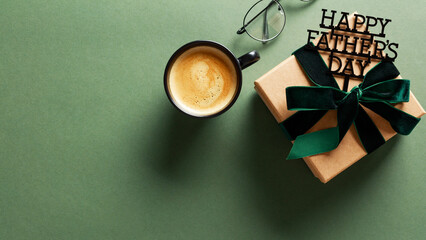 Fathers Day concept with glasses, coffee, and gift on a green background. Ideal for greeting cards or ads
