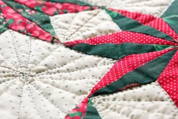 Closeup patchwork or quilt with christmas star motifs in green, red and white.	