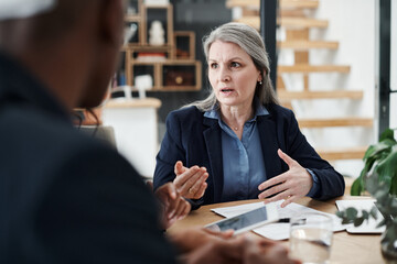 Mature leader, woman and meeting with tablet at desk for strategy, explanation and discussion with employees. Female director, talk and faq in office with team for business, teamwork or management