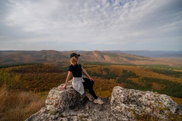 Fototapeta premium woman on mountain peak looking in beautiful mountain valley in autumn. Landscape with sporty young woman, blu sky in fall. Hiking. Nature