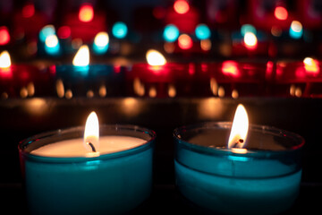 Velas acesas e coloridas iluminam o interior escuro e sereno de uma Igreja