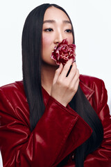 Mysterious woman with black hair and red leather jacket holding a flower in front of her face