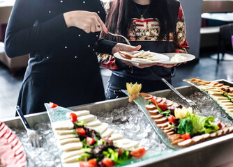 Two Women Standing Together, Each With a Plate of Food