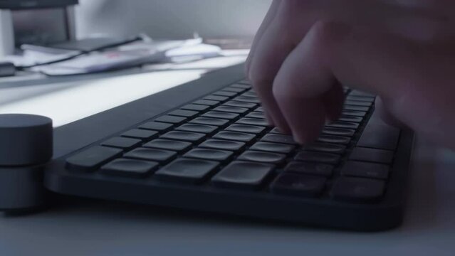 Close-up of a man's hands working on a keyboard and screen.