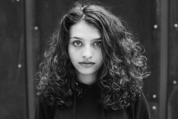 White brunette teenage girl with curly hair poses on the street in the city.