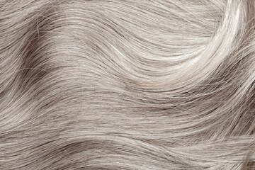 Blond hair close-up as a background. Women's long blonde hair. Beautifully styled wavy shiny curls....