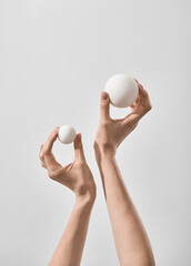 Female hands Holding two balls of different Sizes On a simple background