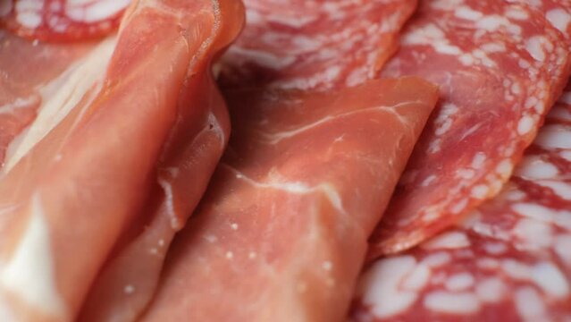 Cold cuts, salami, jamon and sausages spinning close-up.
