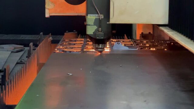 The iron plate is being cut into a pattern using an automatic laser cutting tool