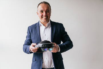 A businessman in a suit demonstrates a virtual reality headset, smiling broadly, indicating...