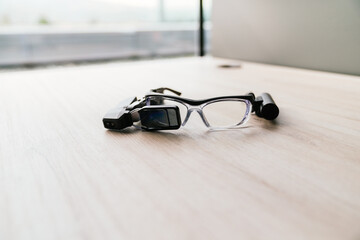 A pair of smart glasses placed on a desk, showcasing the integration of wearable technology in a...