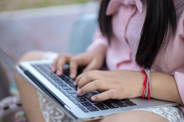 Close up of little asian girl sitting on the stairs with laptop study outdoors