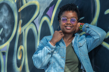 black smiling urban woman posing on graffiti wall