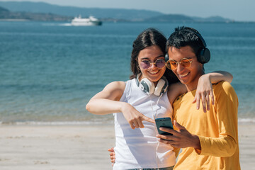 young couple enjoying on the beach with headphones