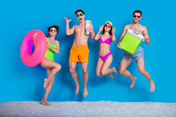 Full length photo of positive impressed buddies company dressed bikini going picnic jumping high isolated blue color background