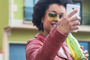 African American woman with vintage glasses taking a selfie or live video with the phone
