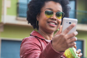 African American woman with vintage glasses taking a selfie or live video with the phone