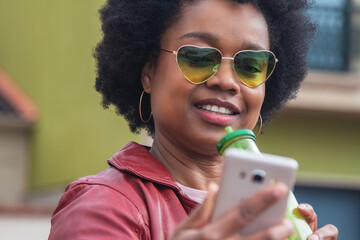 urban woman with vintage glasses using phone and drinking