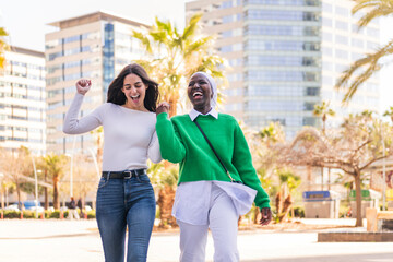 two women laughing happy at city holding hands